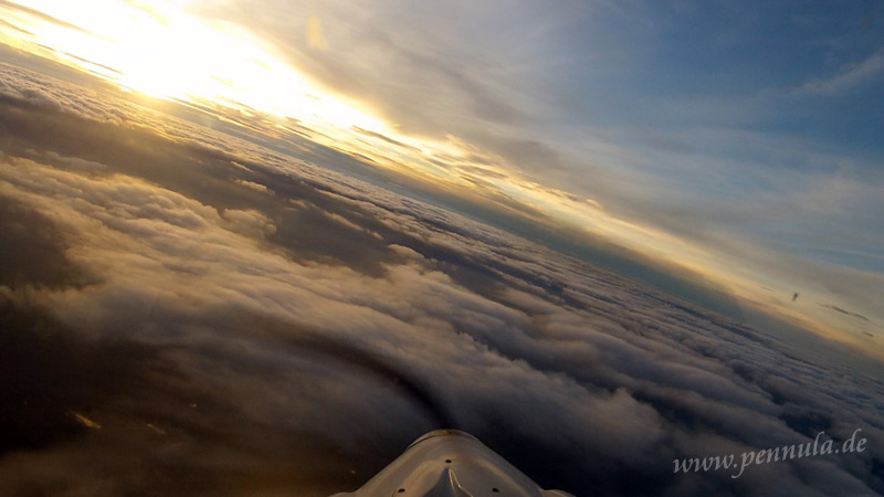 Goldene Lichtstrahlen erstrecken sich über die gesamten Wolken vor dem Flugzeug